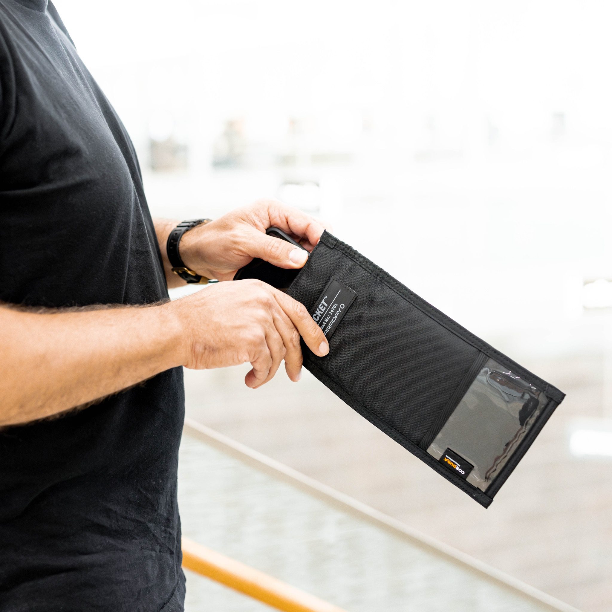 Person holding a black wallet with a smartphone inside.