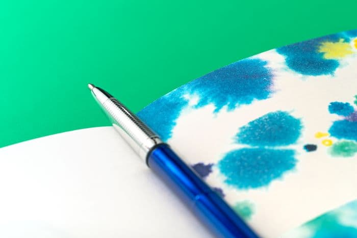 Blue pen resting on a white and blue patterned surface.